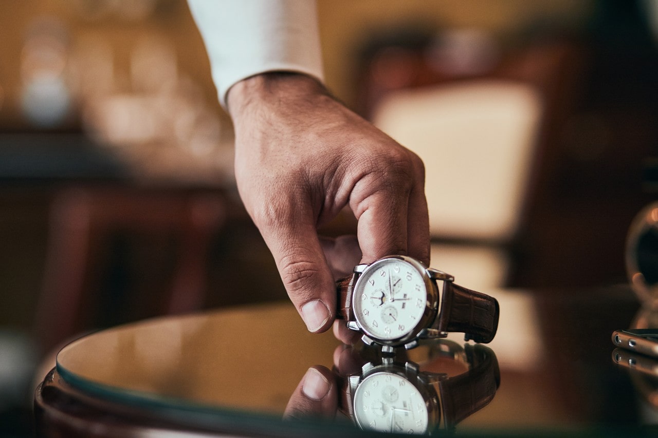a person in a long sleeve shirt setting down a watch on a table