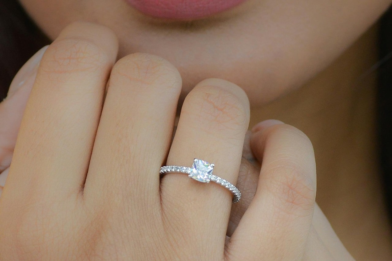 A halo engagement rings with an eternity band on a woman’s hand