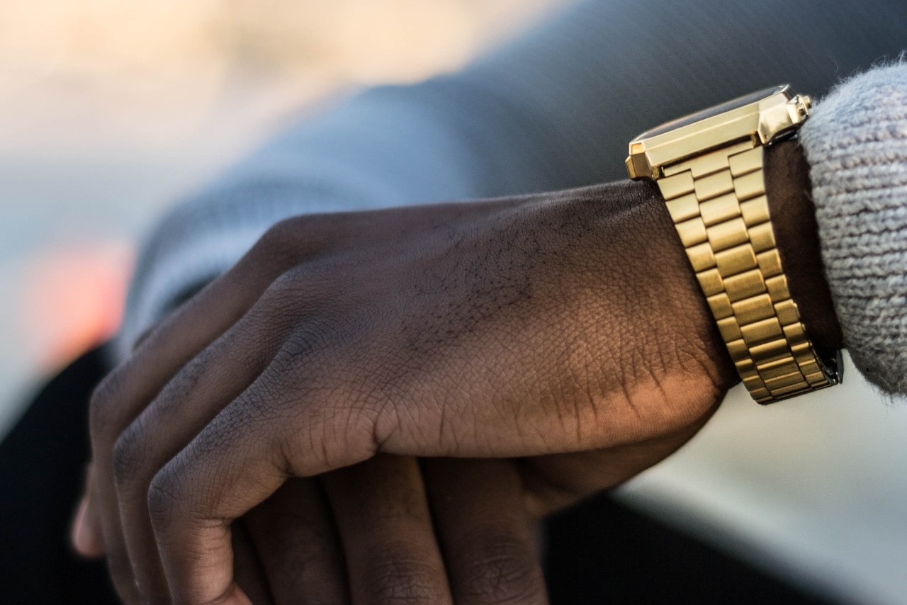 a man’s hand wearing a gold watch