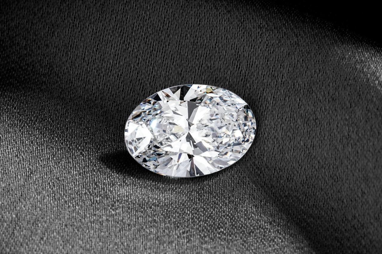 an oval cut diamond sitting on a piece of gray fabric