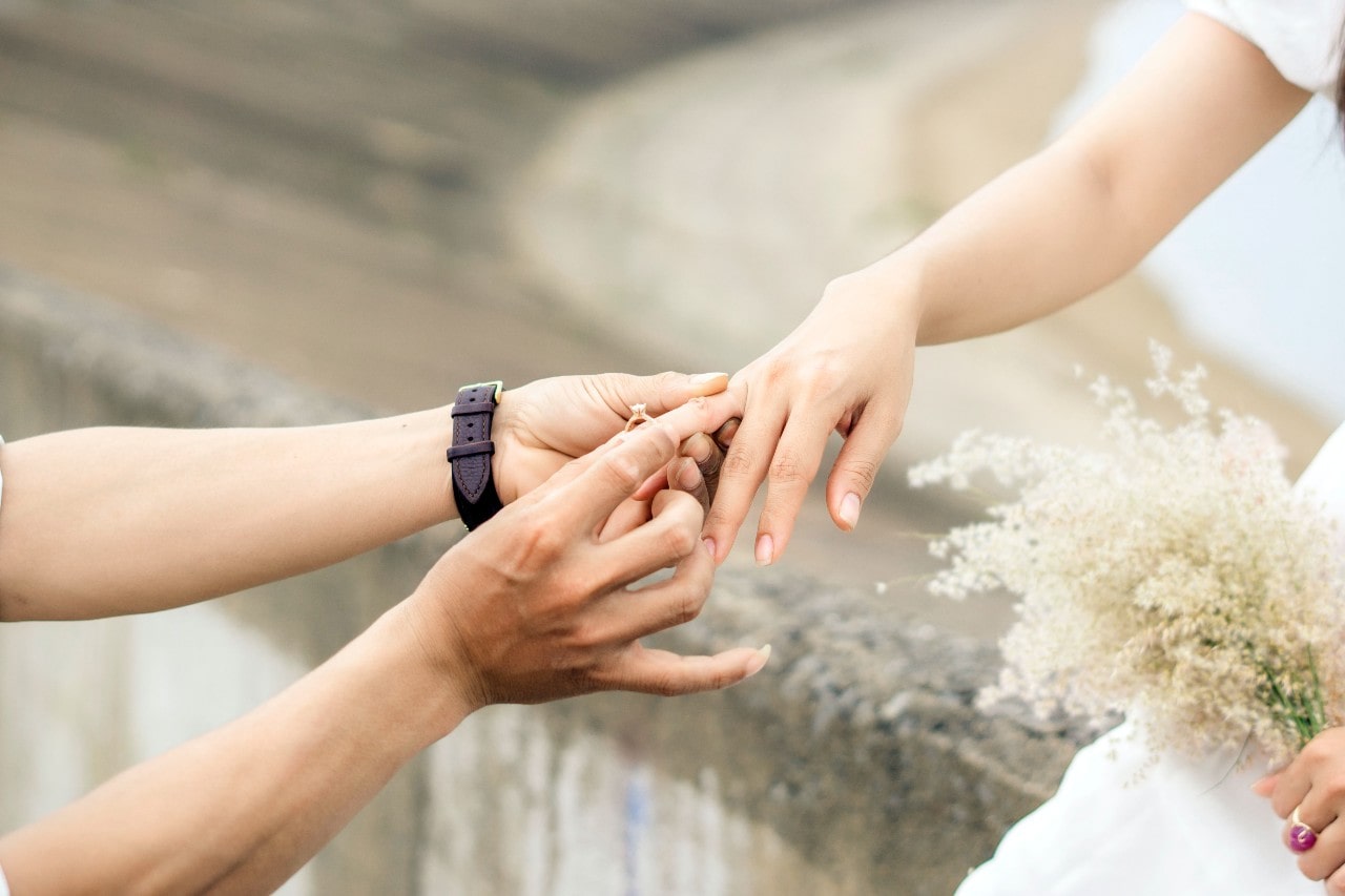 a man placing an engagement ring on a woman’s finger