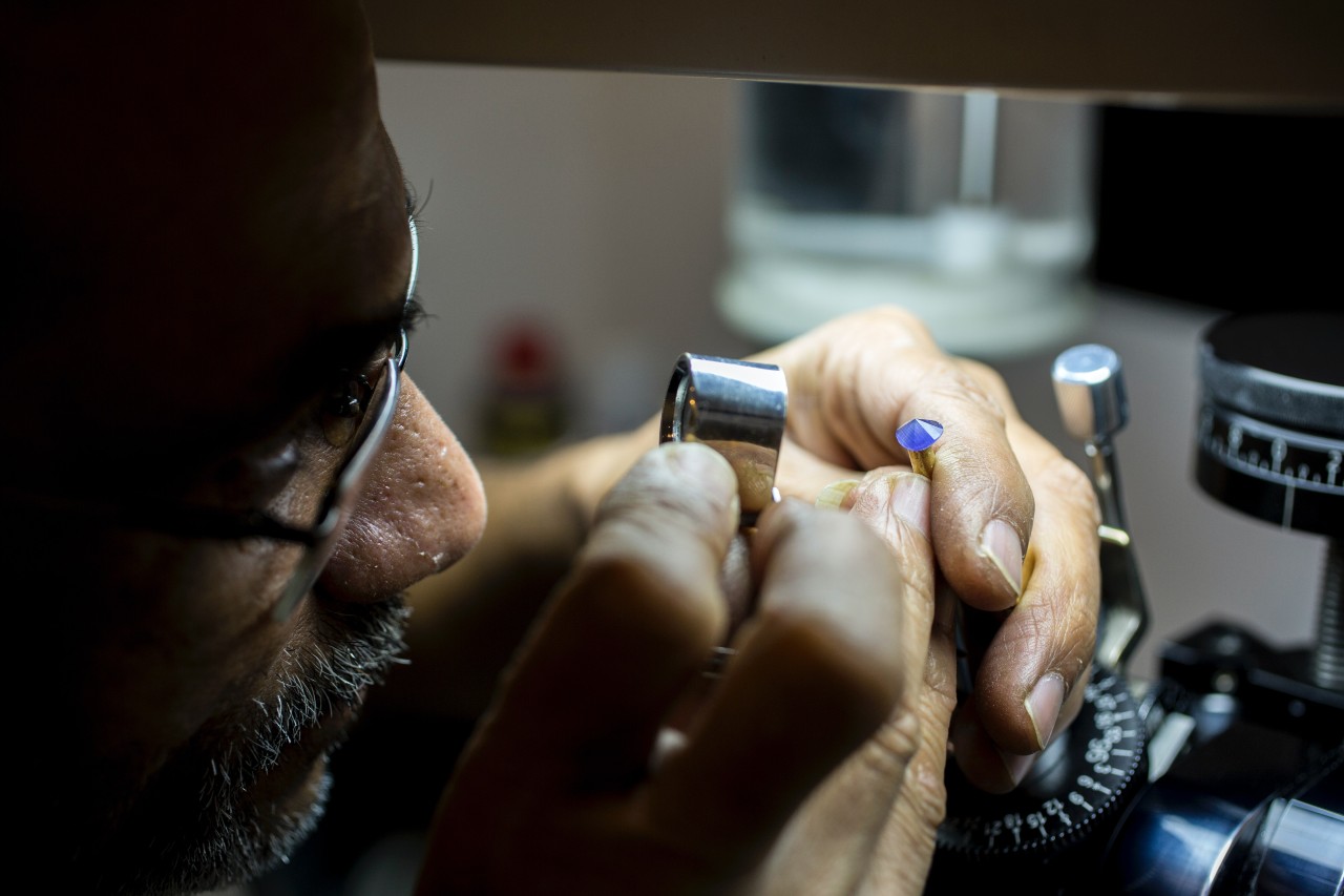 A jeweler examining a gemstone through a small magnifying glass.