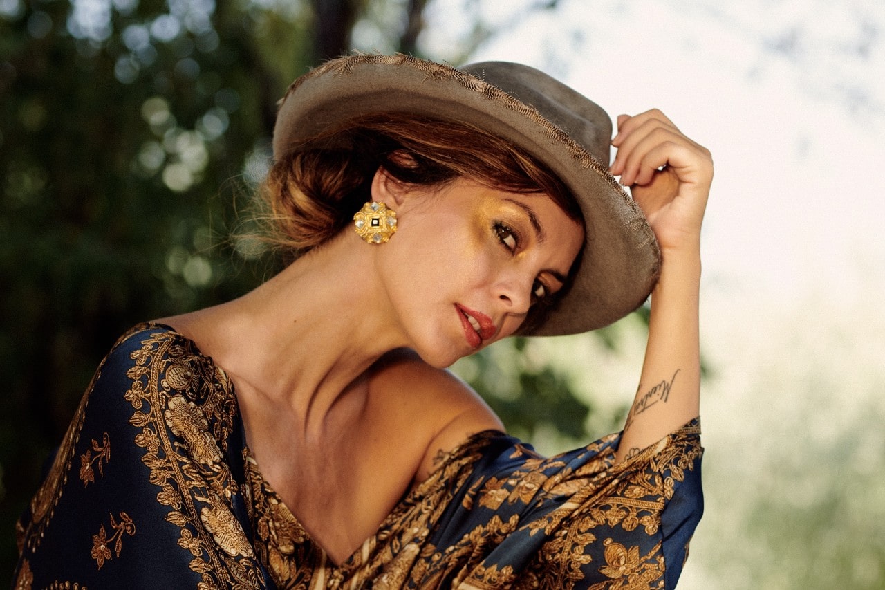 A shot of an elegantly dressed woman wearing bold gold earrings.