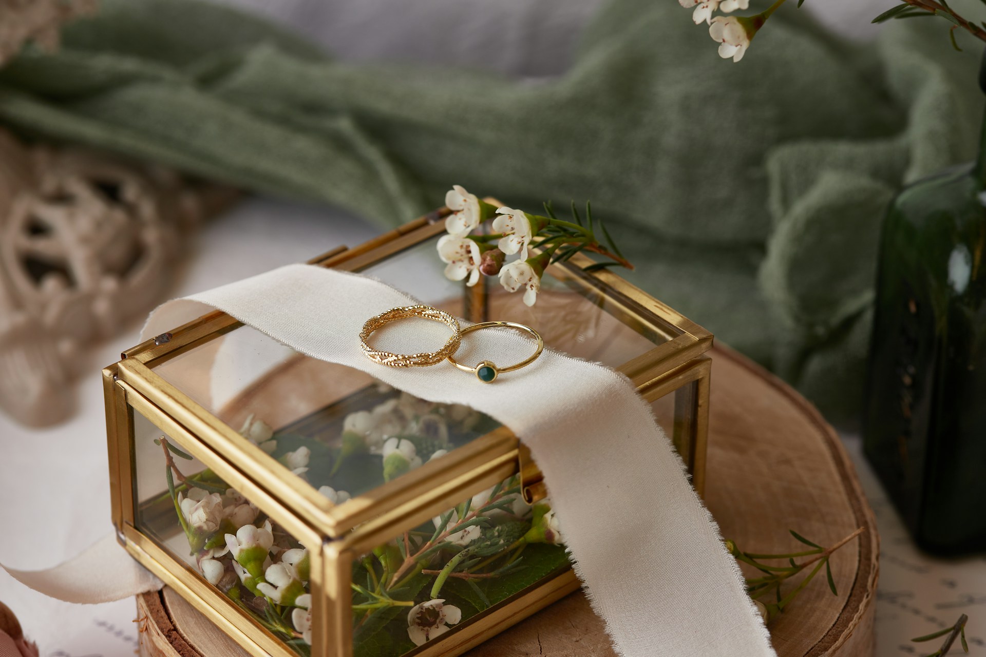 A view of a simple yet elegant jewelry box full of flowers, with two gold wedding bands displayed on top. 