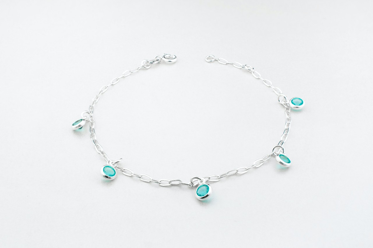 a white gold chain bracelet featuring blue bezel set gemstones.