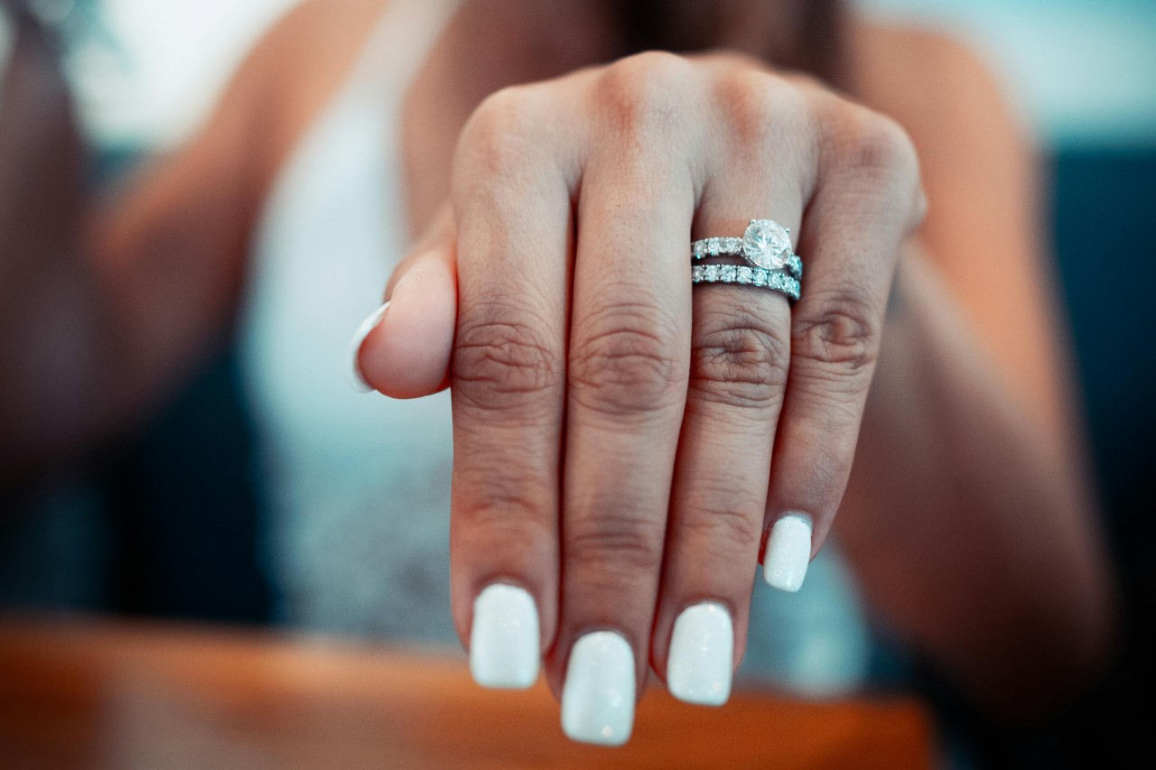 A woman’s extended hand adorned with a diamond engagement ring and matching wedding band.